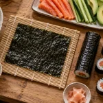 Comment faire des sushi : riz vinaigré, nori et maki sur planche bois